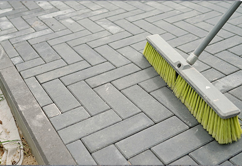 broom sweeping a patterned paved surface with a focus on cleanliness and maintenance tips for 5 star results